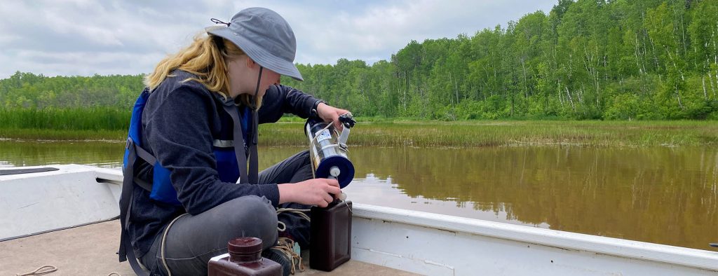 A woman sitting in a boat on a river testing water samples