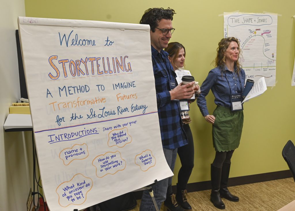 A man and two women next to a wall chart during engage in a lively networking session on storytelling.