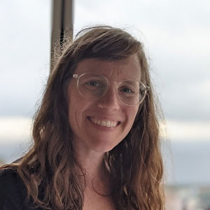 A smiling woman with long brown hair and glasses